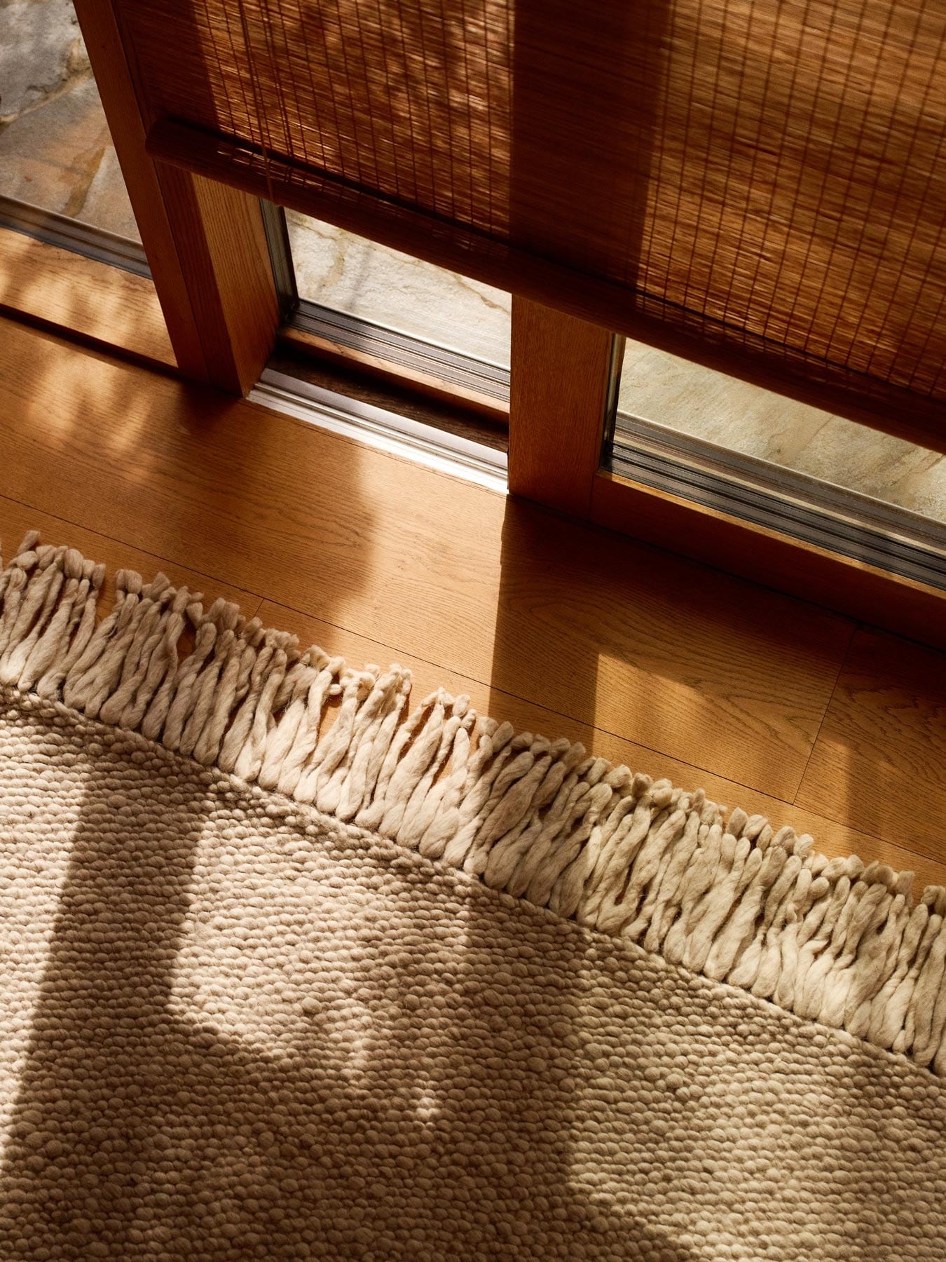 White rug with fringes in front of a window