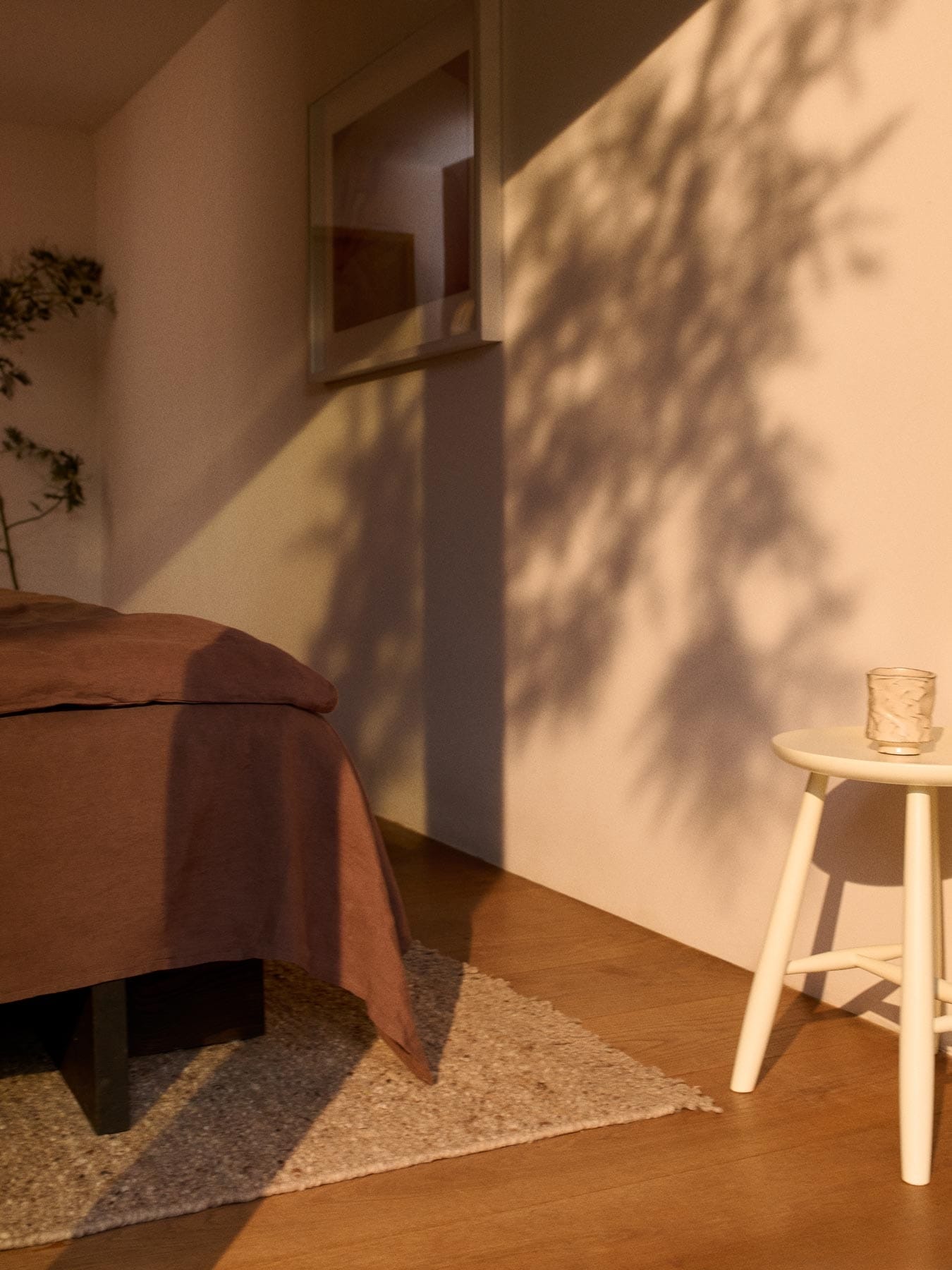 beige wool rug and stool at the foot of a bed